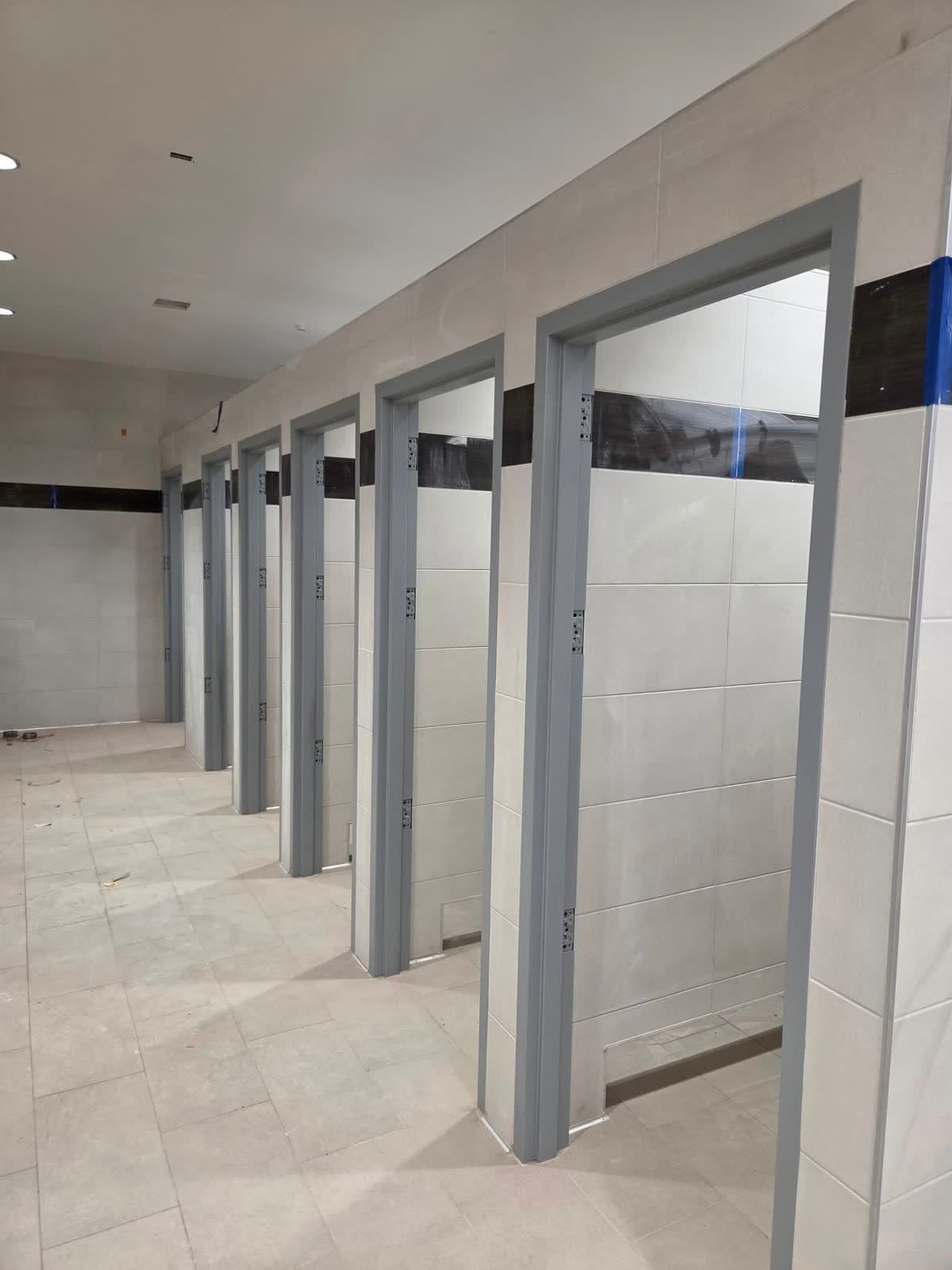 The same restroom finished, with painted partitions and clean cut lines at the walls and ceiling