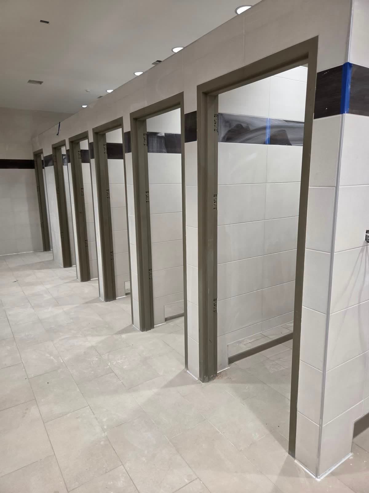 Row of restroom stall partitions and block walls before any painting