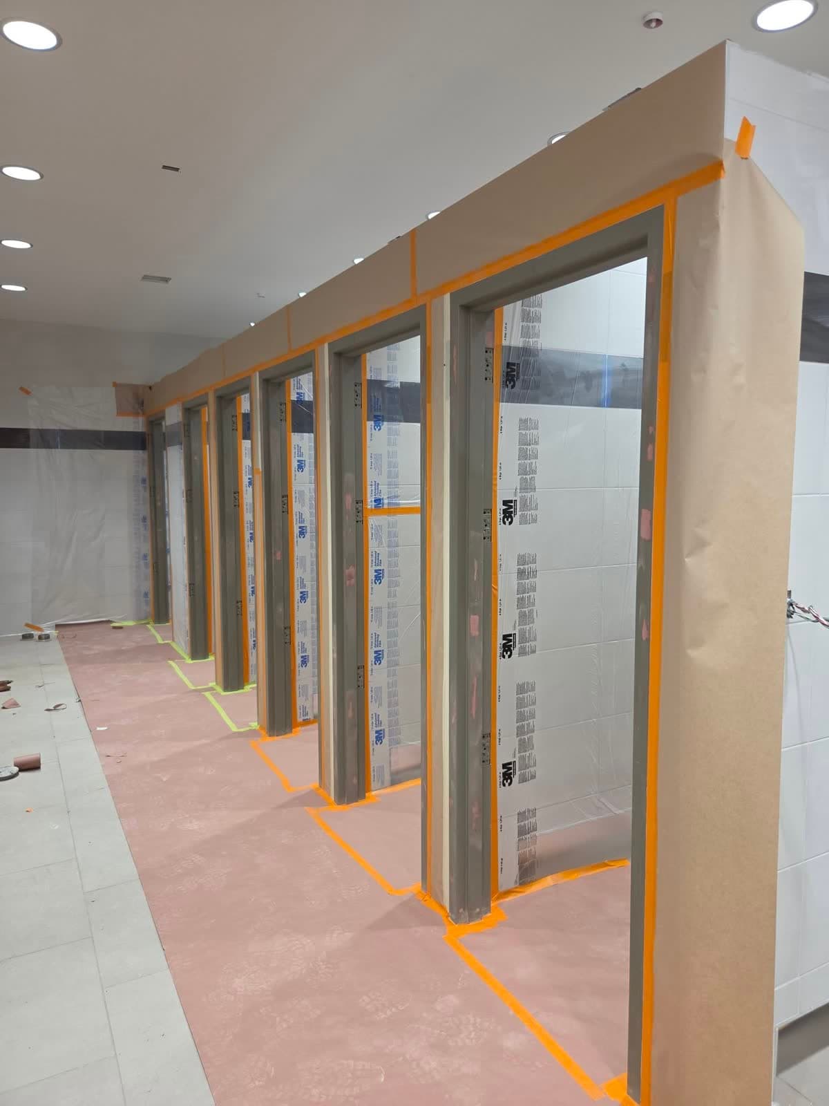 The same restroom with partitions, floors and fixtures fully masked in paper and tape